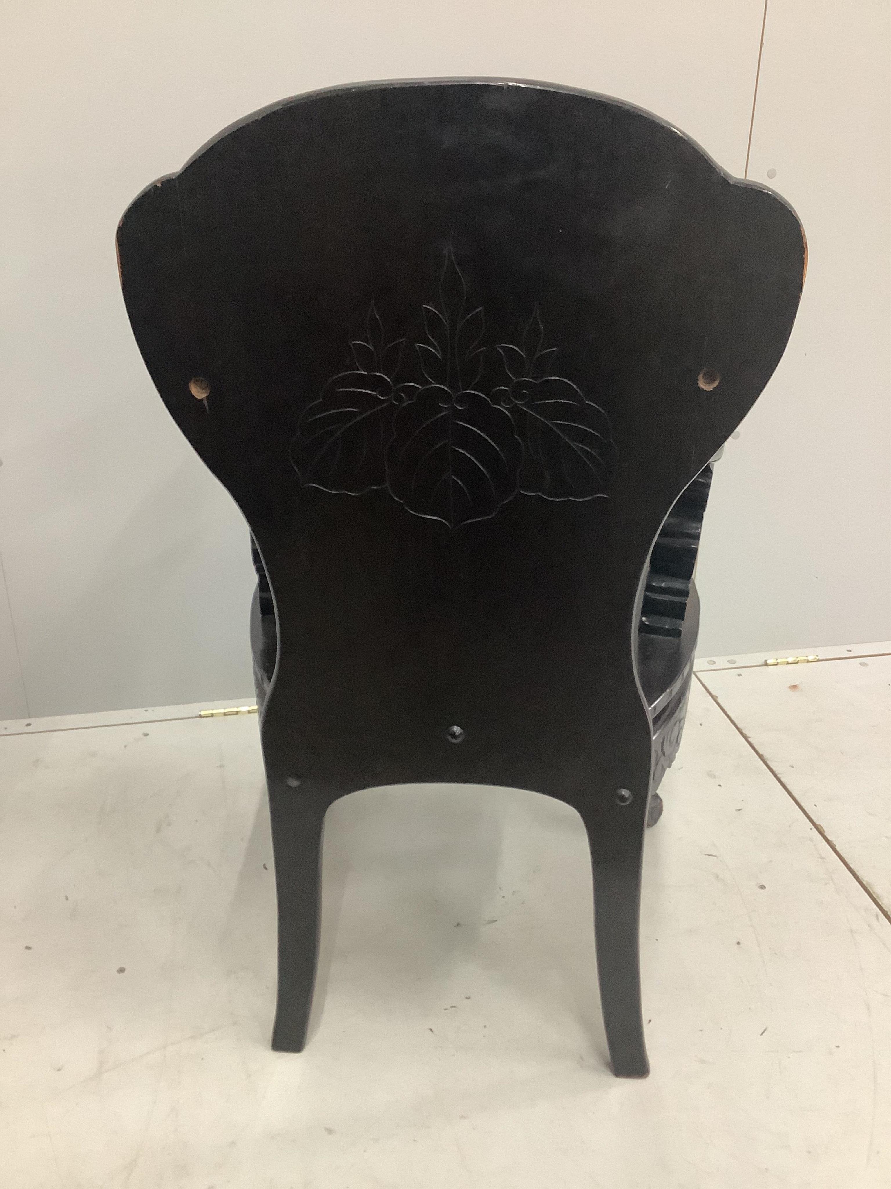 An early 20th century Chinese ebonised and carved hardwood elbow chair with dragon arms, width 60cm. Condition - poor